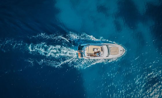 Aerial top view of a luxury yacht cruising through deep blue water