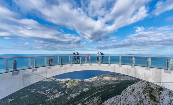 Visitors standing on the glass Skywalk bridge on Biokovo Mountain with dramatic views of the Adriatic coastline below