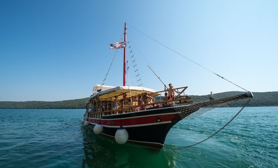 Traditional wooden excursion boat sailing on the Adriatic Sea along the Croatian coastline on a sunny day
