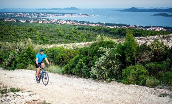 Cyclist riding on a gravel trail overlooking Dubrovnik coastline and Adriatic Sea