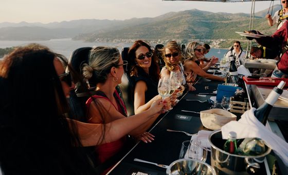 Guests enjoying wine tasting during Dinner in the Sky experience above Dubrovnik with coastal views in the background