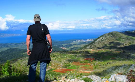 Traveler overlooking vineyards, hills, and the Adriatic coast from a scenic viewpoint during a wine tour on Hvar Island