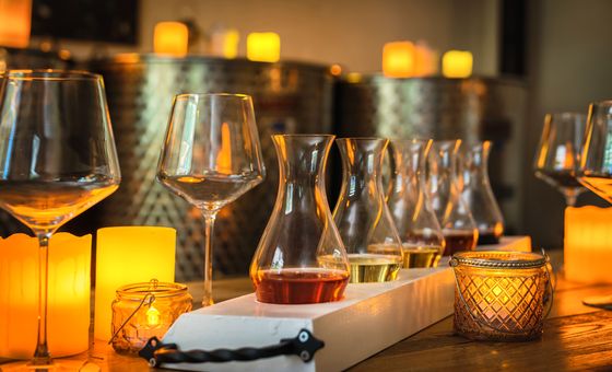 Wine tasting flight with multiple small glasses in a cozy winery tasting room illuminated by warm candlelight
