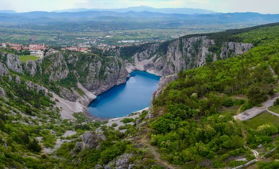 Panoramic view of Blue Lake (Modro Jezero) near Imotski, surrounded by steep limestone cliffs and green hills