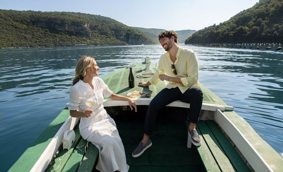 Guests enjoying a private oyster tasting aboard a small boat on the Limski channel