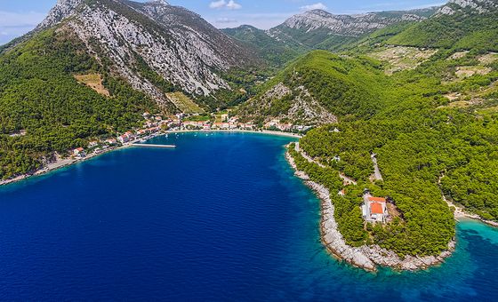Aerial view of Trstenik Bay on the Pelješac Peninsula, with a curved shoreline, clear blue sea, and green hills
