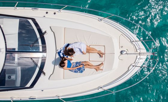 Aerial top view of two women sunbathing on the bow of a luxury motor yacht